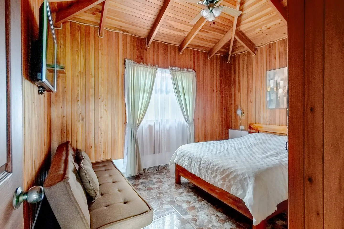 Poas Cottage bedroom with bed, futon, and natural light
